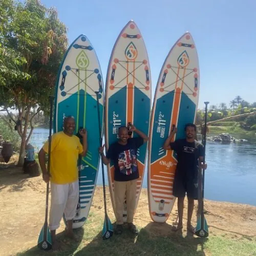The Aswan SUP Rental team with their paddleboards on the riverbank